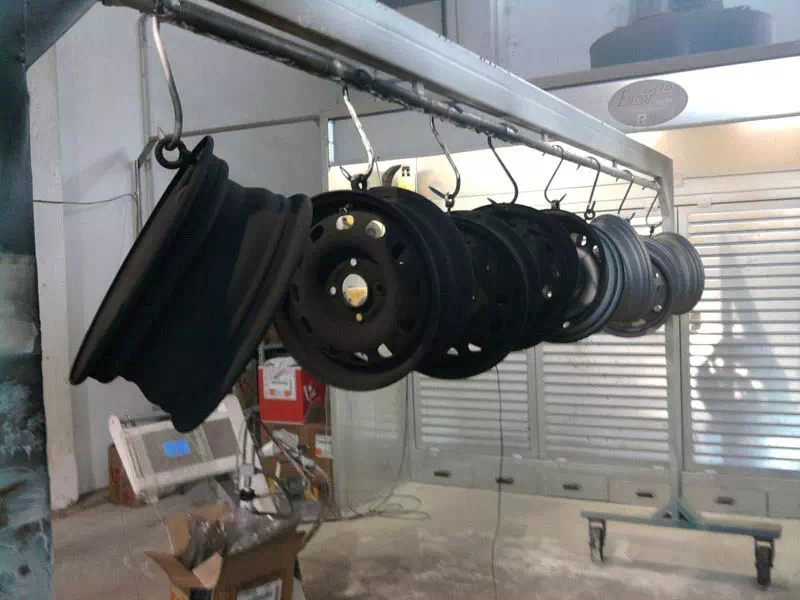 Verniciatura industriale di cerchi in metallo per automotive Cerchi metallici appesi in cabina per processo di verniciatura industriale